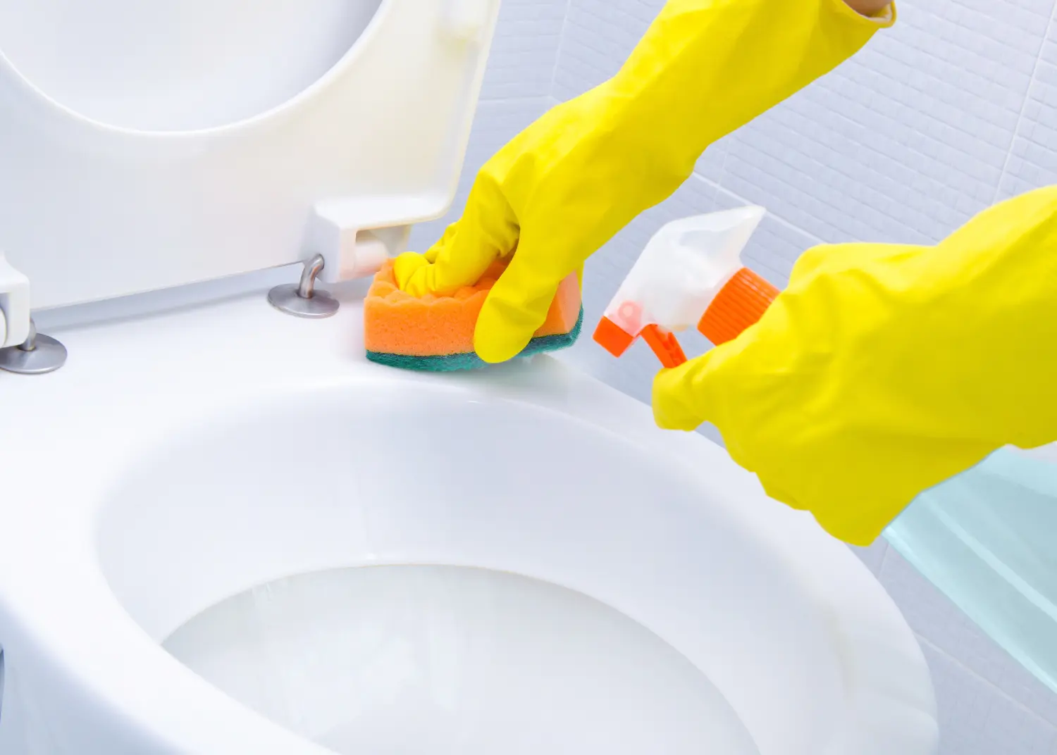 Hände auf gelben Handschuhen beim Reinigen eines WCs
